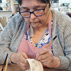 A photo of a woman making a sketch on a bowl